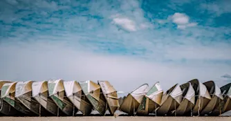 Flera båtar uppradade på en strand med blå himmel