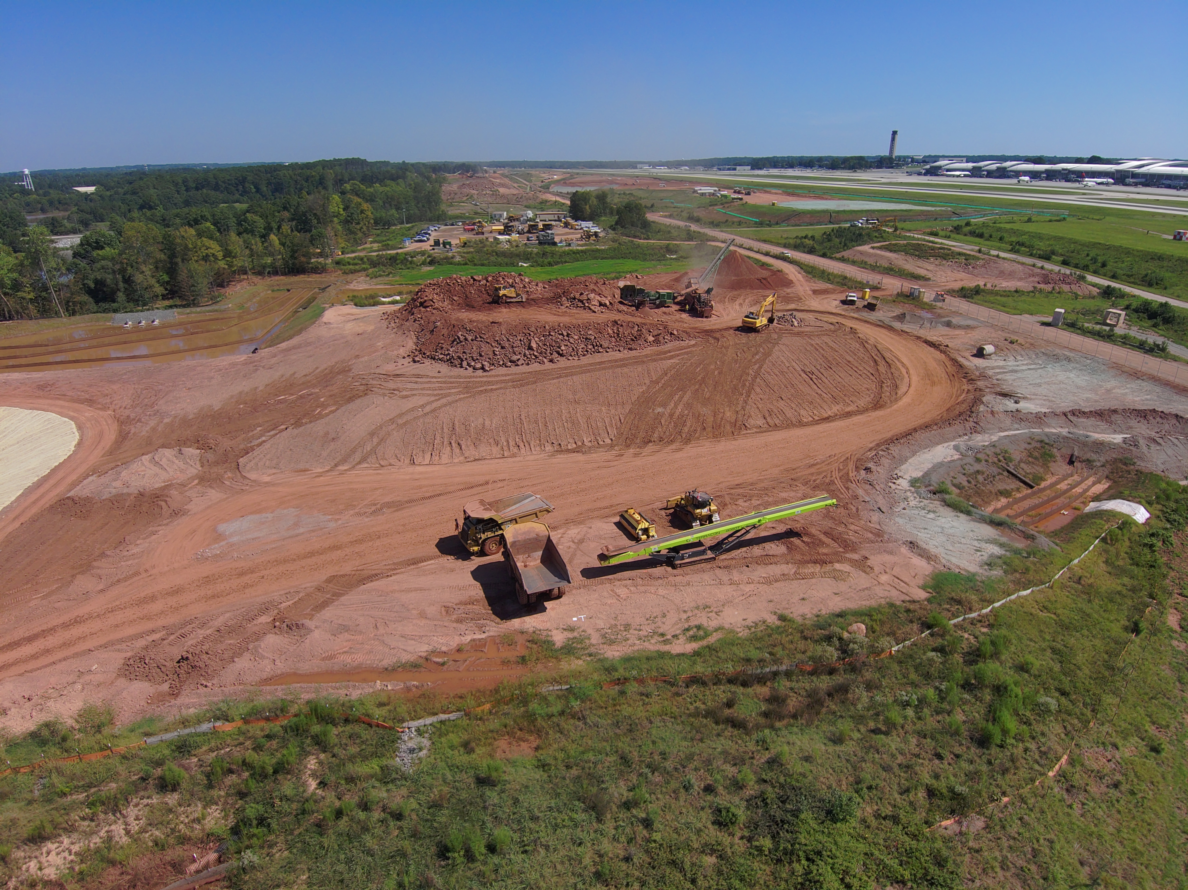 Construction at the site of RDU Airport's new runway, with the terminal and air traffic control tower in the background.