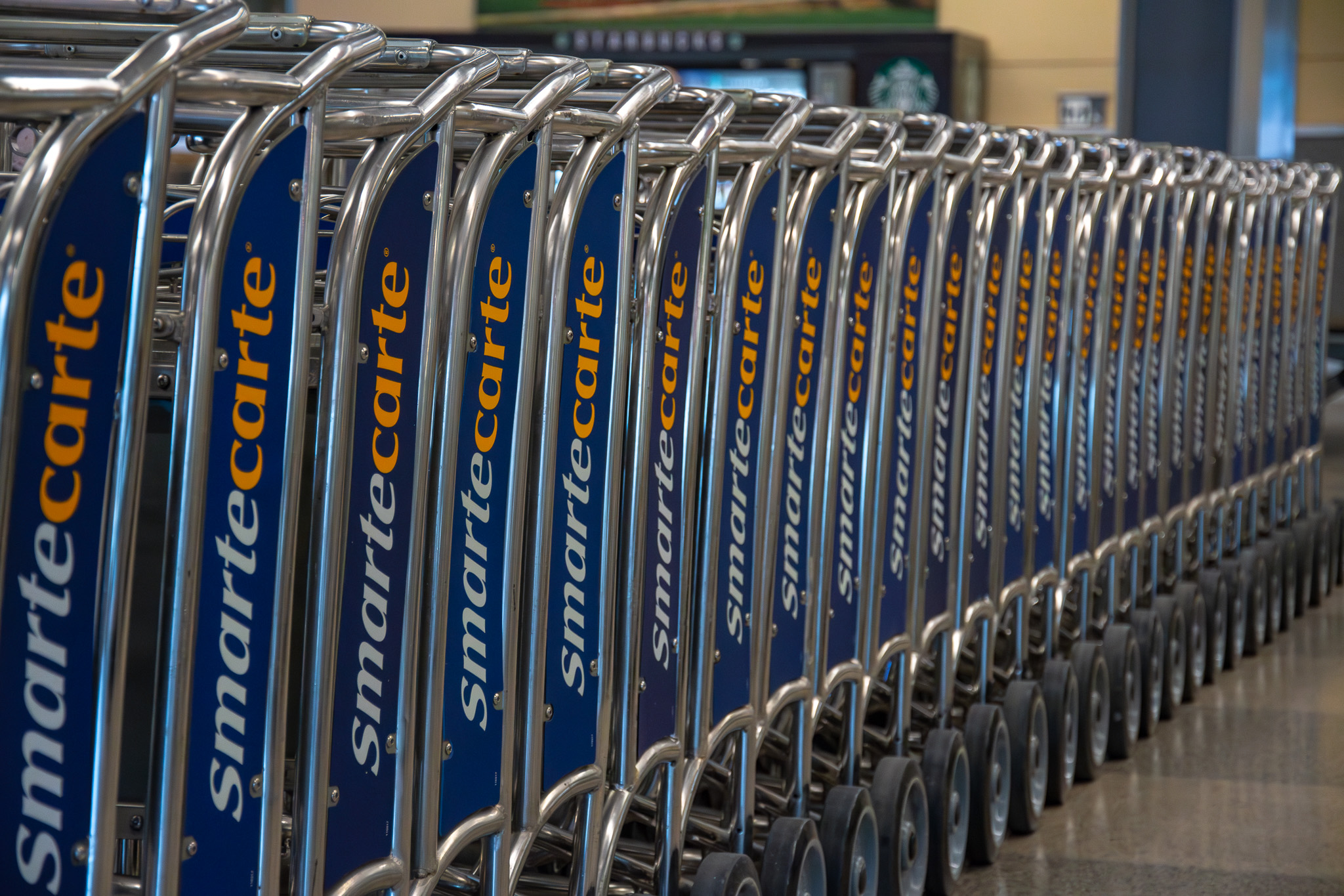 Row of blue and silver shopping carts with Smartecarte branding lined up in an airport terminal.
