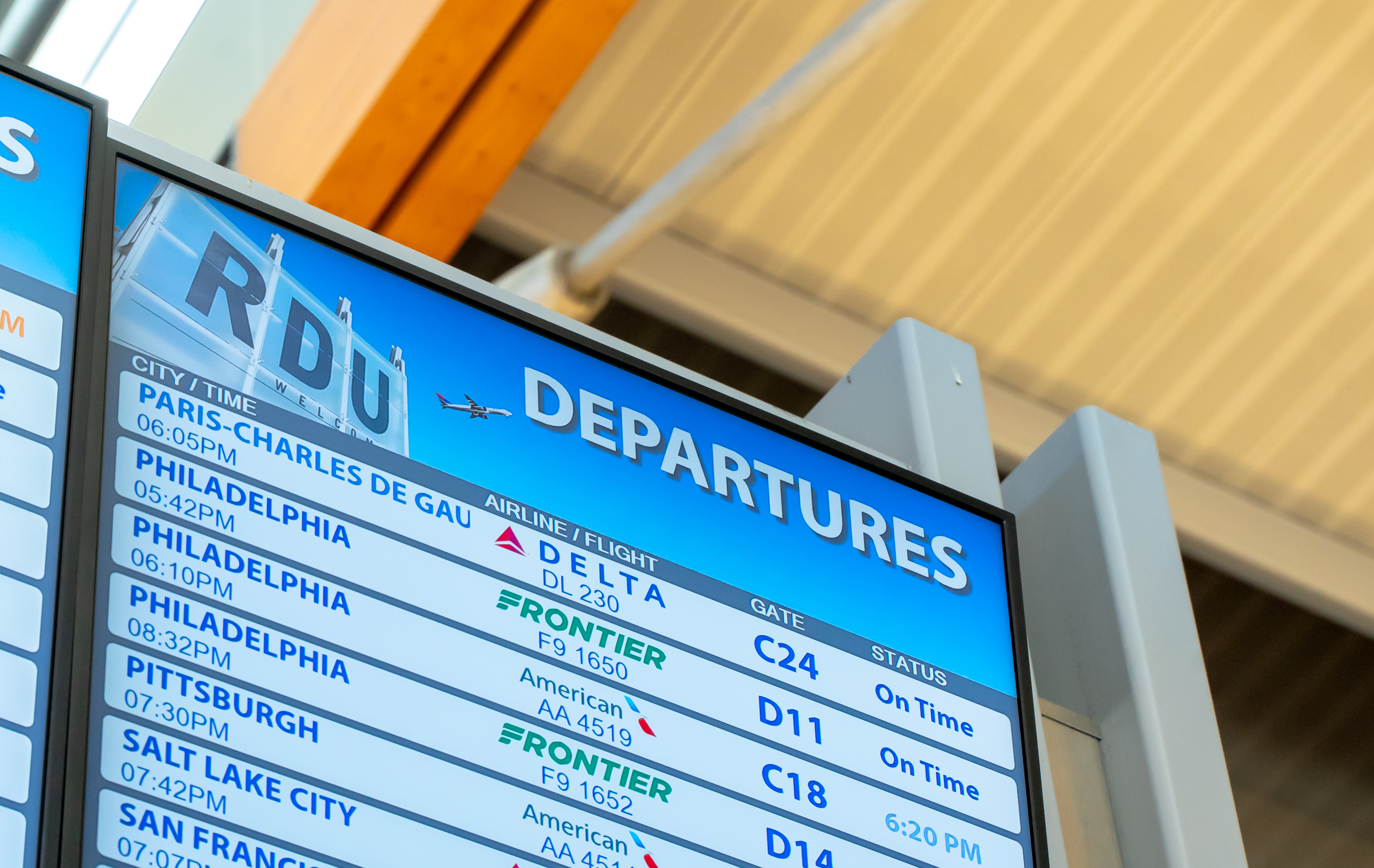 Airport departures board displaying flight information including destinations, airlines, gates and on-time status.