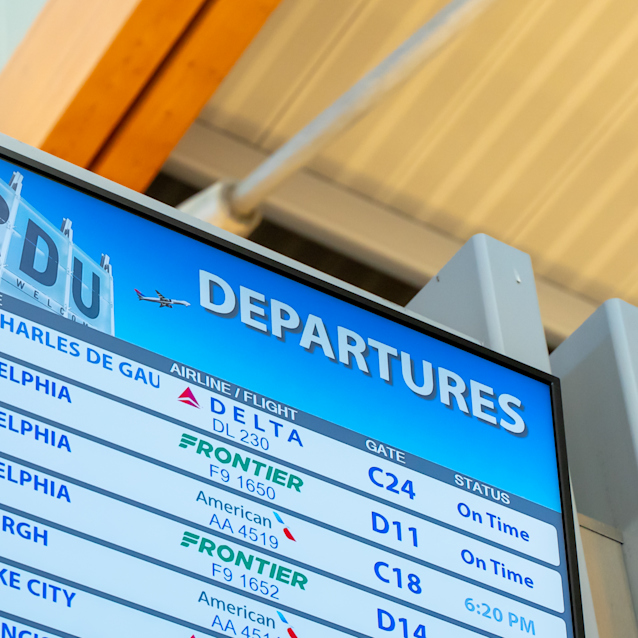 Airport departures board displaying flight information including destinations, airlines, gates and on-time status.