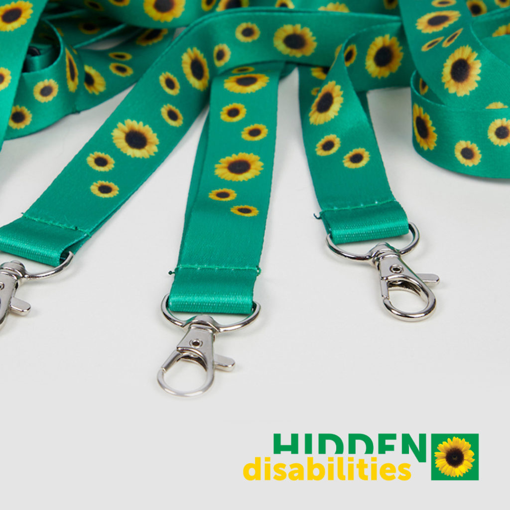 Teal lanyards with yellow sunflower pattern and silver clasps displayed on white surface with Hidden Disabilities logo.