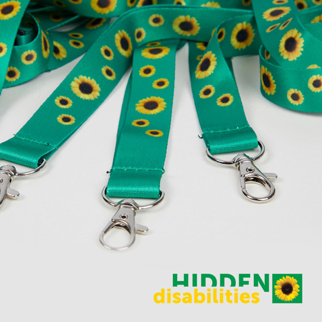 Teal lanyards with yellow sunflower pattern and silver clasps displayed on white surface with Hidden Disabilities logo.