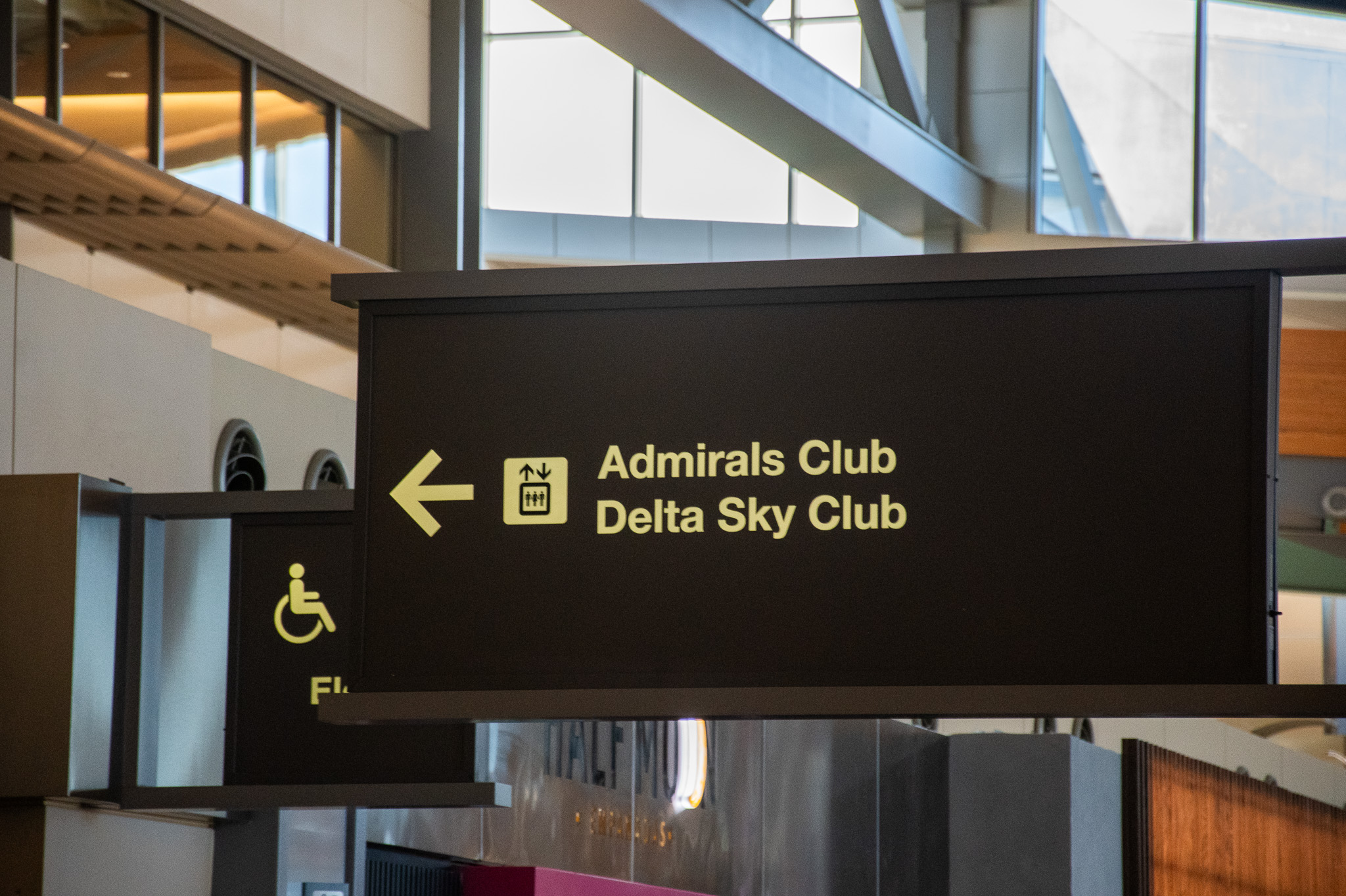 Airport directional sign showing Admirals Club and Delta Sky Club with arrows.
