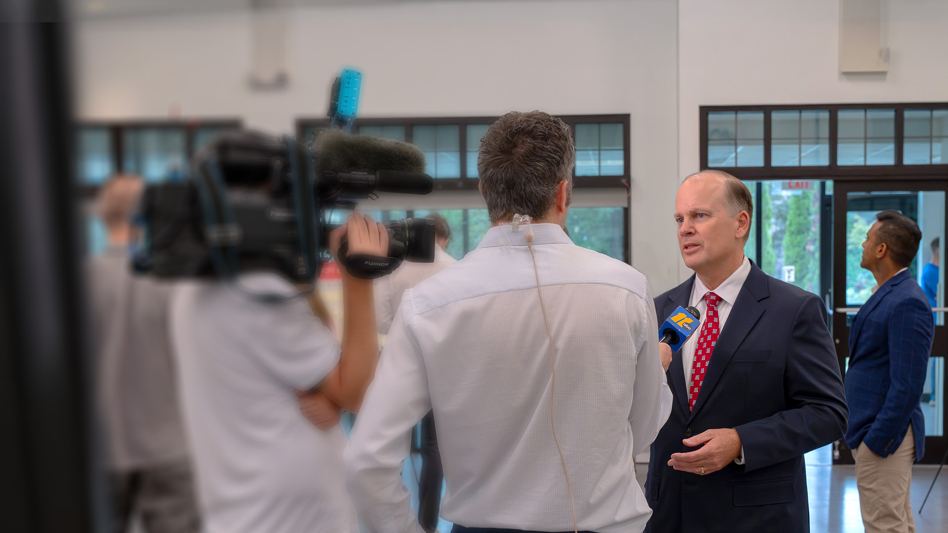 Michael Landguth, President and CEO of the Raleigh-Durham Airport Authority, being interviewed by news reporters. The reporters are holding a camera and a microphone.
