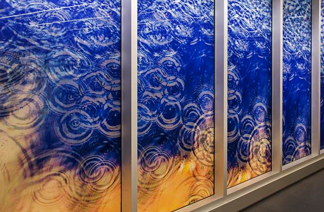 Four vertical glass panels with blue and orange gradient showing water ripple patterns in white circular designs
