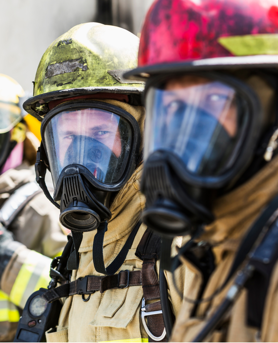 Two firefighters wearing their protective gear and looking at the camera taking the photo