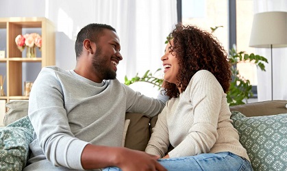 Un couple souriant assis ensemble sur un canapé