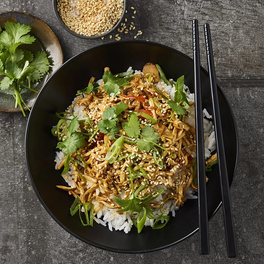 Djup tallrik med ris och wok. Toppad med sesamfrön och korriander. 