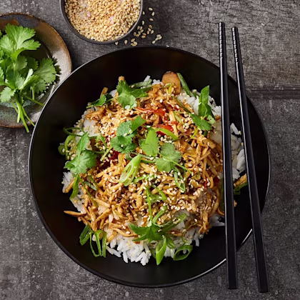 Djup tallrik med ris och wok. Toppad med sesamfrön och korriander.