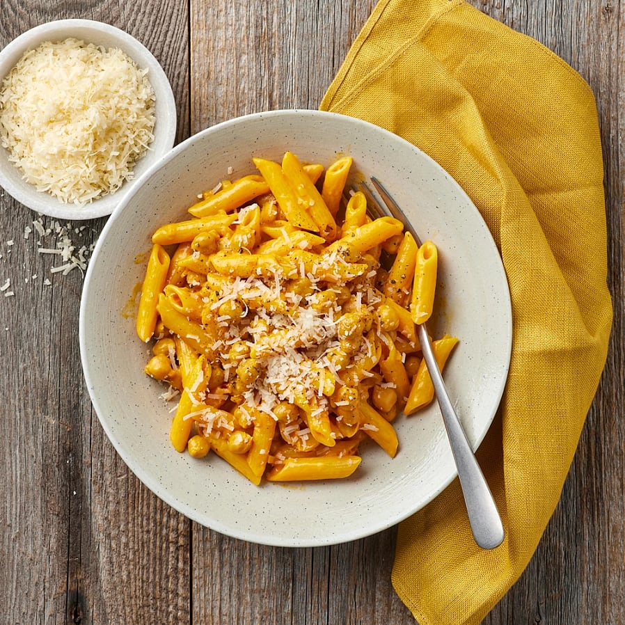 Djup tallrik med pennepasta i en saffransås, toppad med parmesan. 