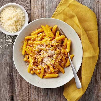 Djup tallrik med pennepasta i en saffransås, toppad med parmesan.