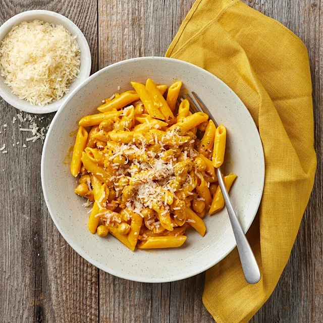 Djup tallrik med pennepasta i en saffransås, toppad med parmesan.
