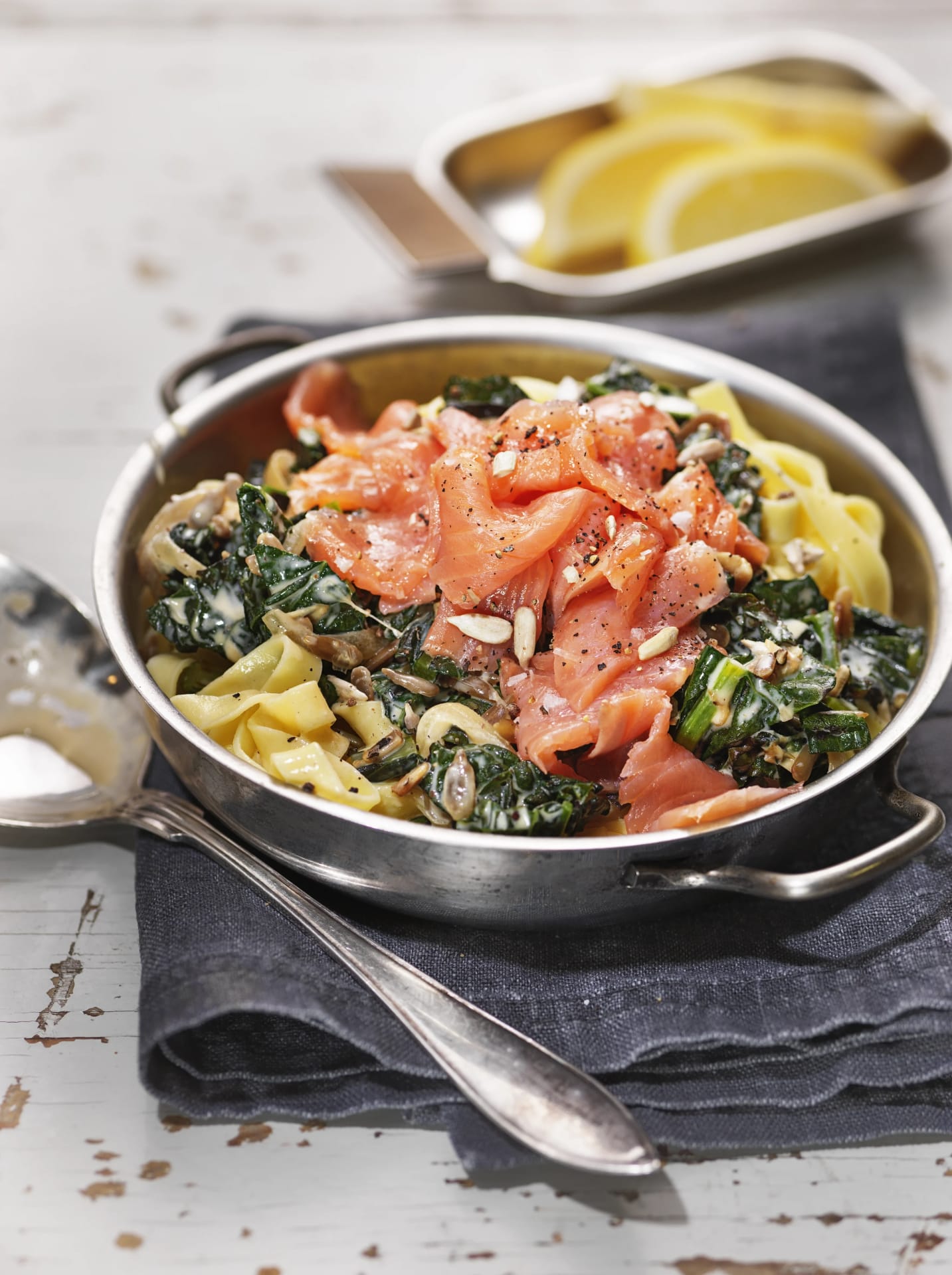 Gravad laxpasta med grönkål i en skål med citronklyftor i en mindre skål bredvid