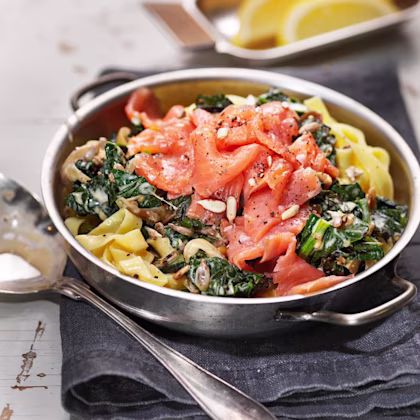 Gravad laxpasta med grönkål i en skål med citronklyftor i en mindre skål bredvid