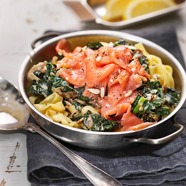 Gravad laxpasta med grönkål i en skål med citronklyftor i en mindre skål bredvid