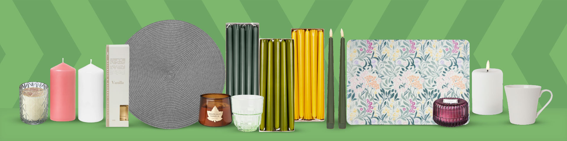 Olika ljus, ljushållare, tallrik, glas, servetter, muggar och ett mönstrat underlägg uppställda på rad. Klicka för att handla ljus.