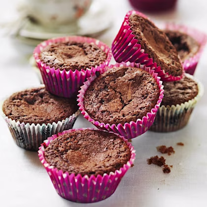 Kladdkakemuffins i färgglada formar upplagda stökigt i en hög.