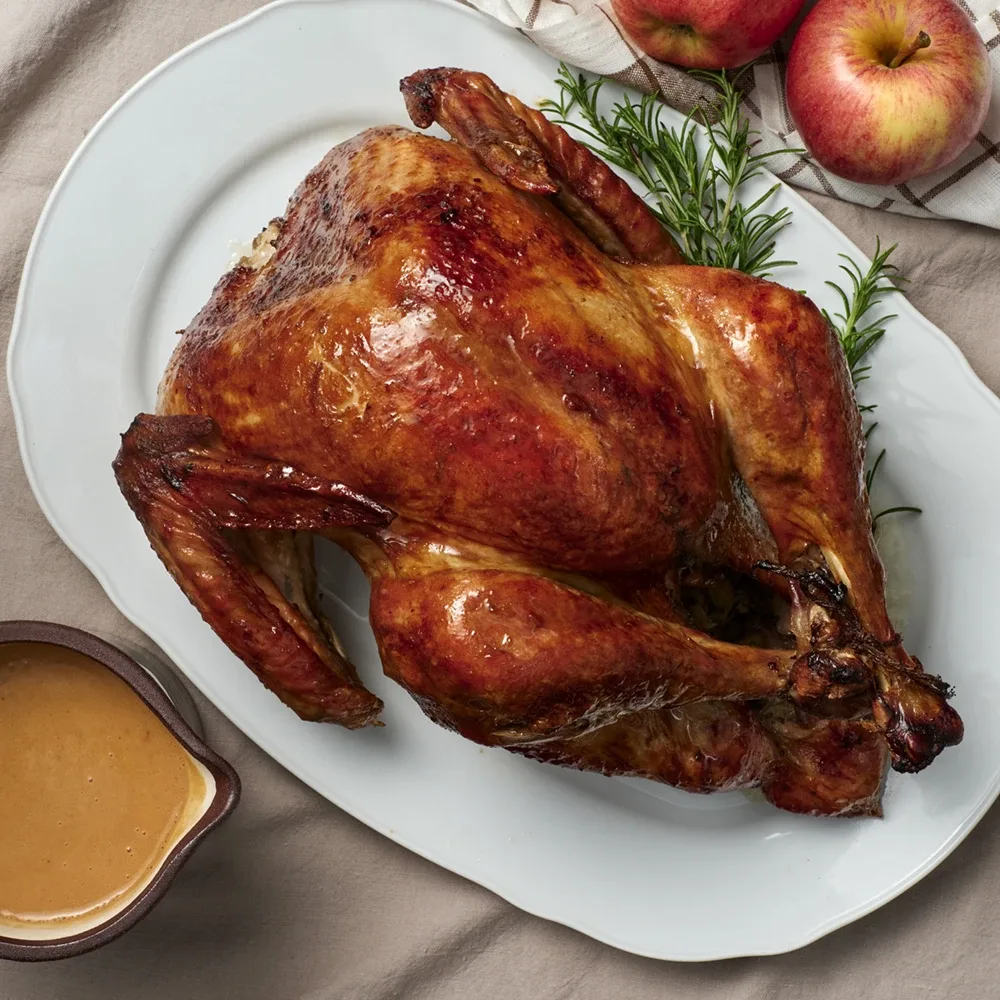 Ett stort vitt fat med en grillad kalkon. 