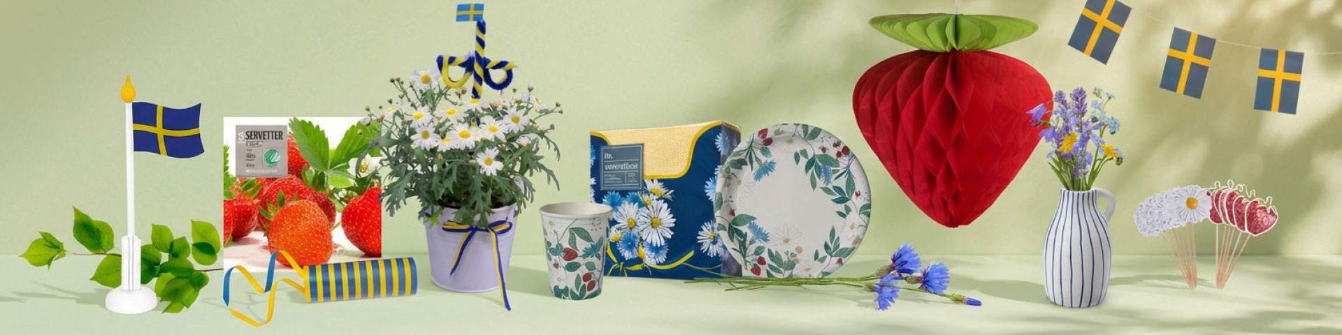 Midsommarpynt med pappersdekoration formad som jordgubbe, engångsartiklar som tallrikar, muggar och servetter med blommotiv, svenska flaggor, jordgubbar och blomsterarrangemang. Klicka för att handla.