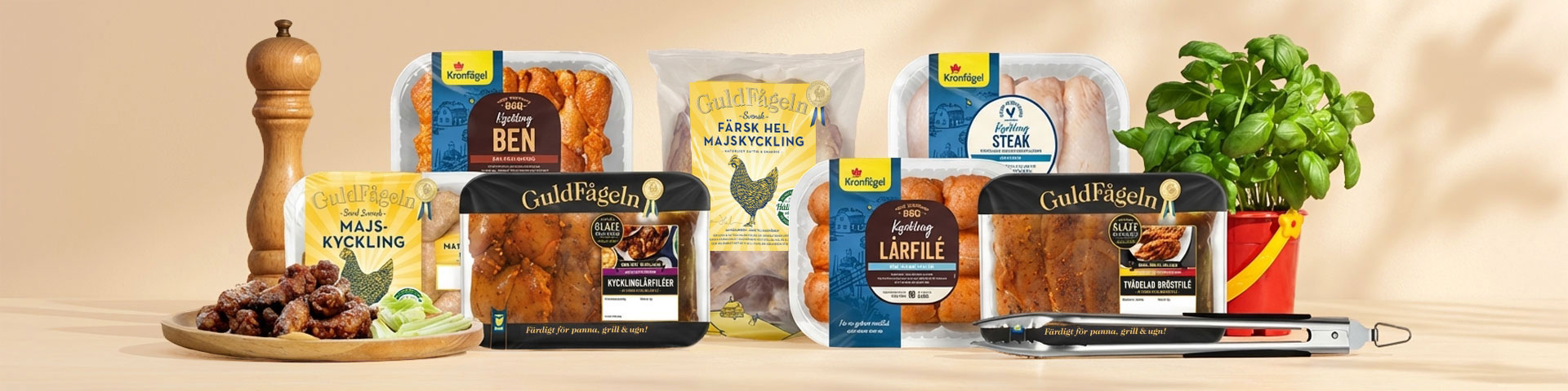 Olika förpackningar med kycklingprodukter från Kronfågel och Guldfågeln, en skål med kycklingbitar, pepparkvarn, basilika i kruka och grilltång. Klicka för att handla kyckling till grillen.