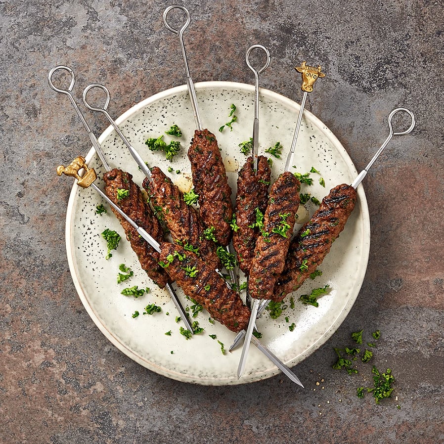 Grillade köttspett med örter på en tallrik, dekorerade med hackad persilja.