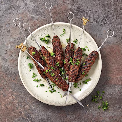 Grillade köttspett med örter på en tallrik, dekorerade med hackad persilja.