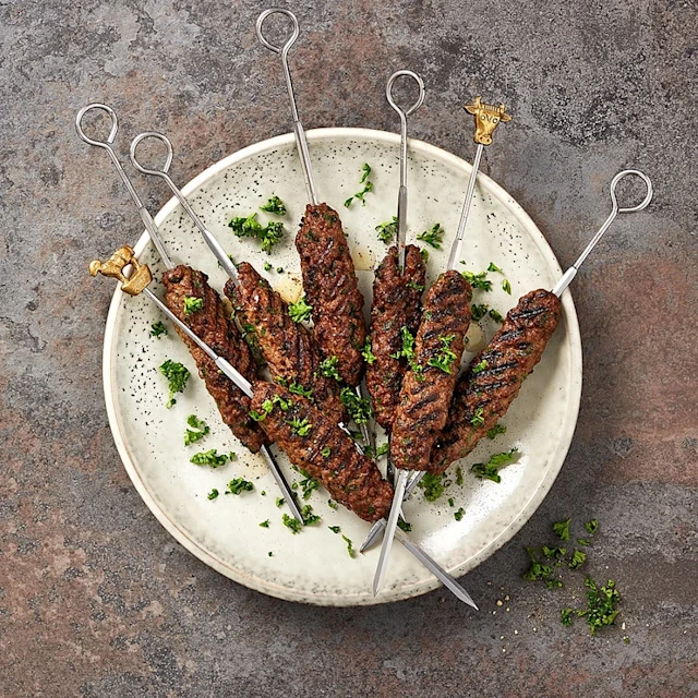 Grillade köttspett med örter på en tallrik, dekorerade med hackad persilja.