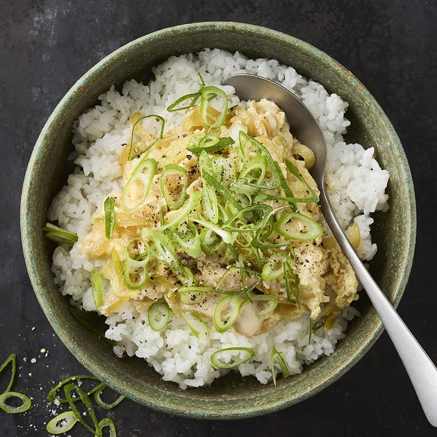 Djup skål med ris. Toppade med en äggröra och salladslök. 