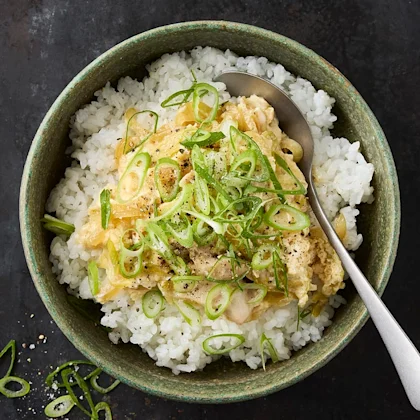 Djup skål med ris. Toppade med en äggröra och salladslök.