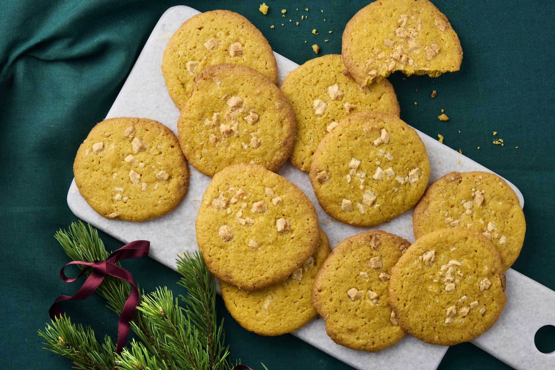 Saffranscookies med bitar av vit choklad på ett fat med granris och rosett.