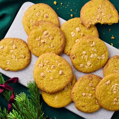 Saffranscookies med bitar av vit choklad på ett fat med granris och rosett.