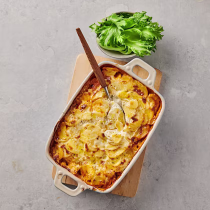 Moussaka i form med salladsblad i en skål bredvid