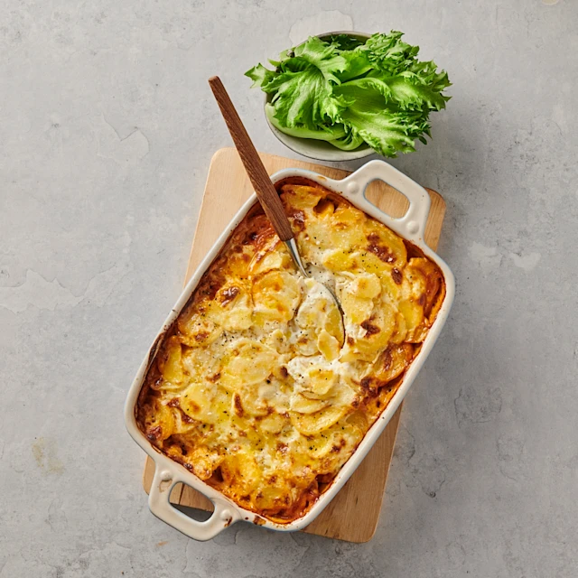 Moussaka i form med salladsblad i en skål bredvid