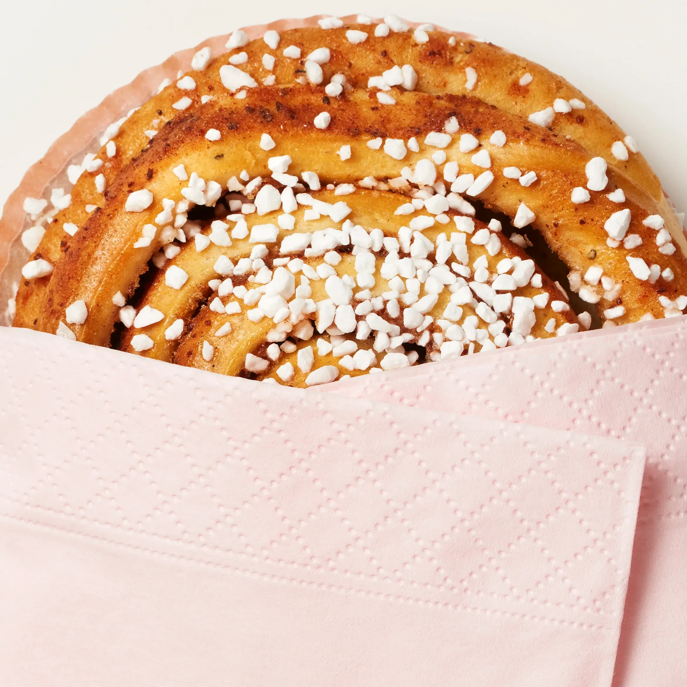 Kanelbullar med glasyr, placerade i en ugnsform på bakpapper.