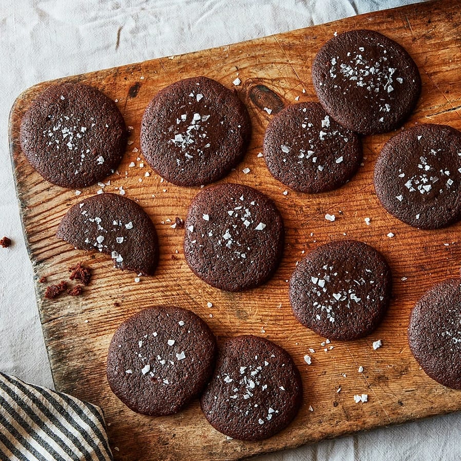 En rustik träbräda med mörkbruna chokladkakor toppade med havssalt. 