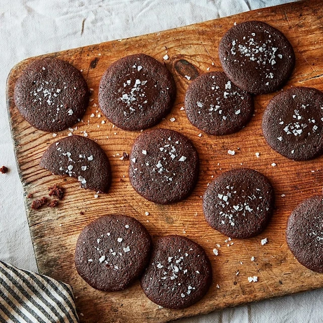 En rustik träbräda med mörkbruna chokladkakor toppade med havssalt.