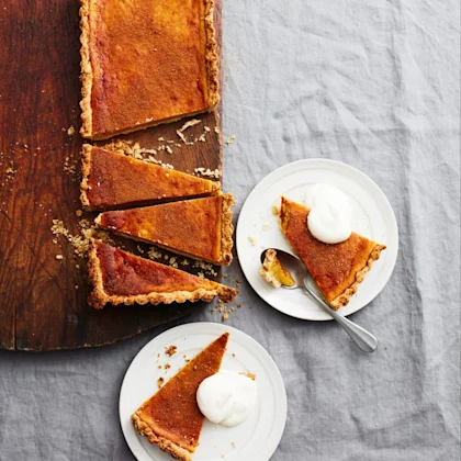 Pumpapaj skuren i bitar på en skärbräda, två bitar serverade på tallrikar med en klick grädde och sked.