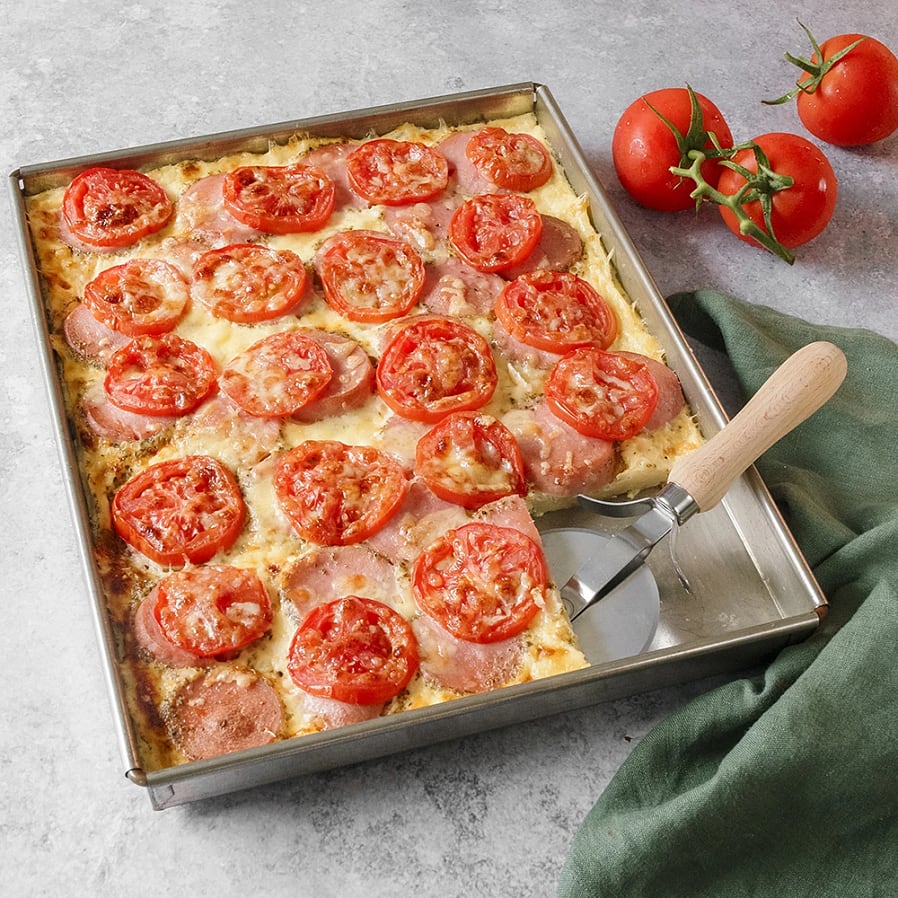 En plåt med smält ost med skivor av tomat och falukorv. 