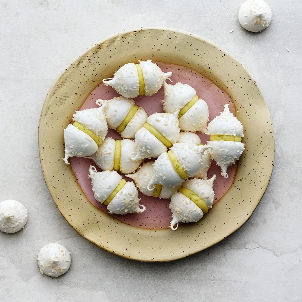 Flera små marängkyssar, maränger med limesmörkräm mellan två maränger på ett fat.