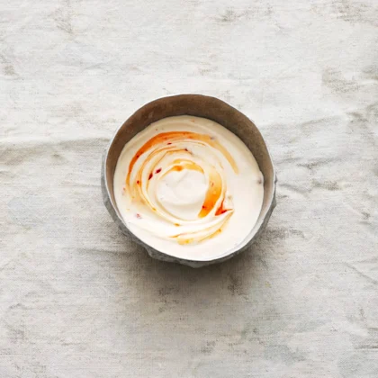 Sweet chilisås med crème fraiche i en skål på en grå duk