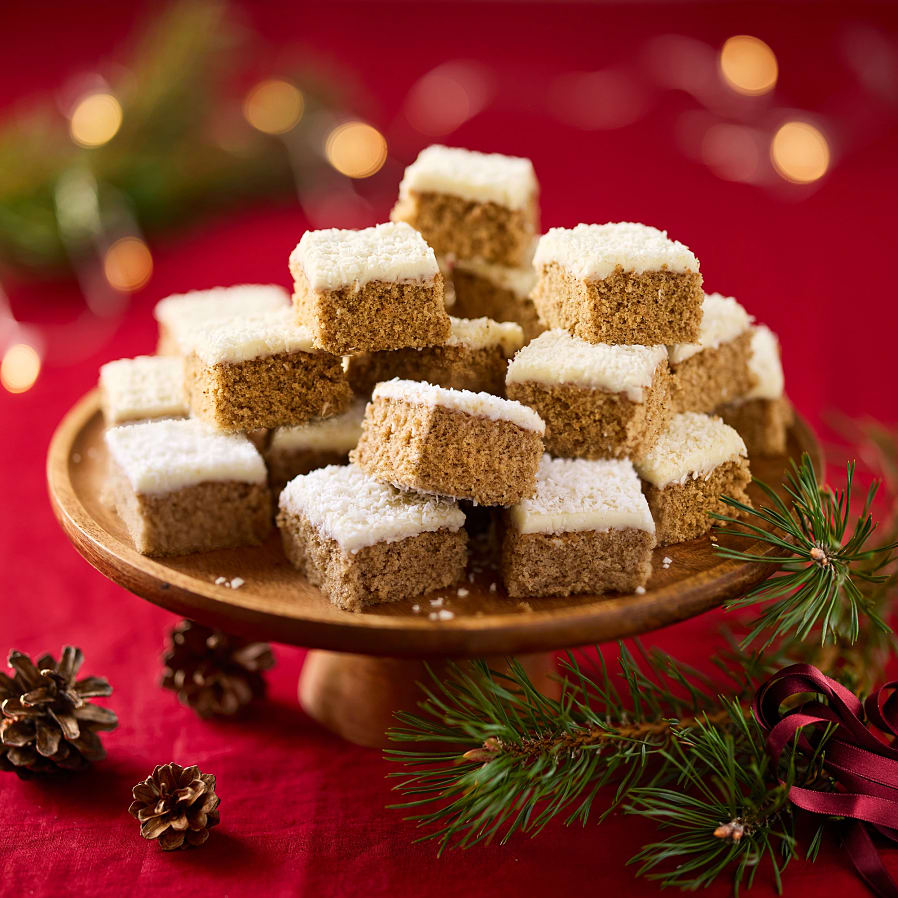 Ett upphöjt fat med bitar av mjuk pepparkaka med glasyr, staplade på varandra. 