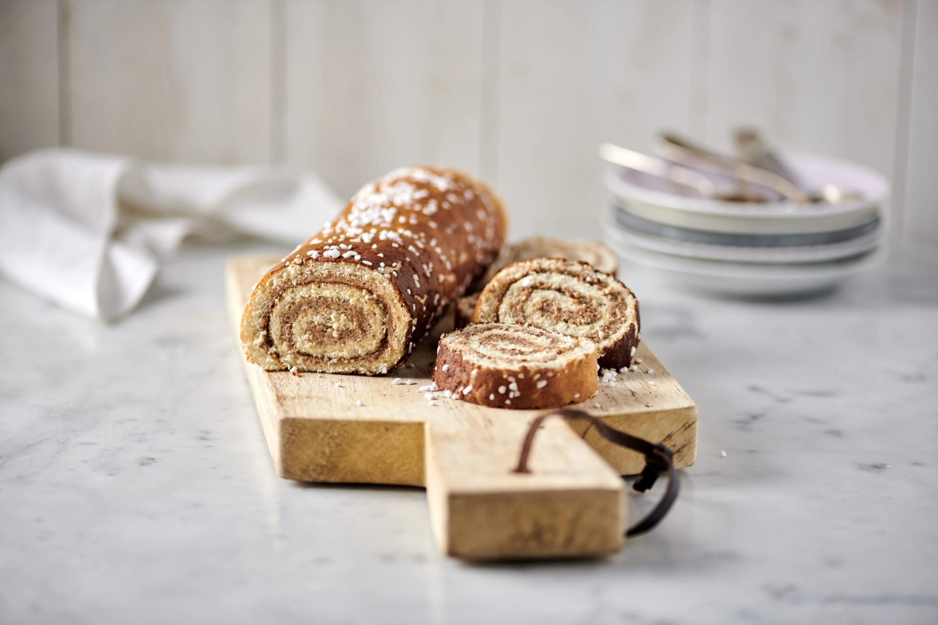 Kanelbullerulltårta på träbräda. Några skivor är uppskurna i framkant.
