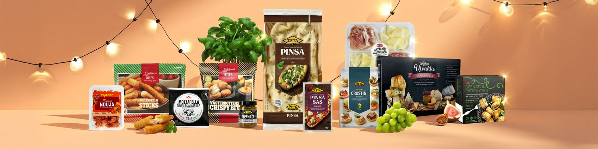 Sortiment av plockmat med pinsa, mozzarella sticks, nduja, ost, charkuterier, crostini, sås, örter och druvor på ett bord, med förpackningar märkta “Pinsa”, “Pinsa sås”, “Mozzarella”, “Mozzarella Sticks”, “Nduja”, “Crostini” och “Antipasto”.