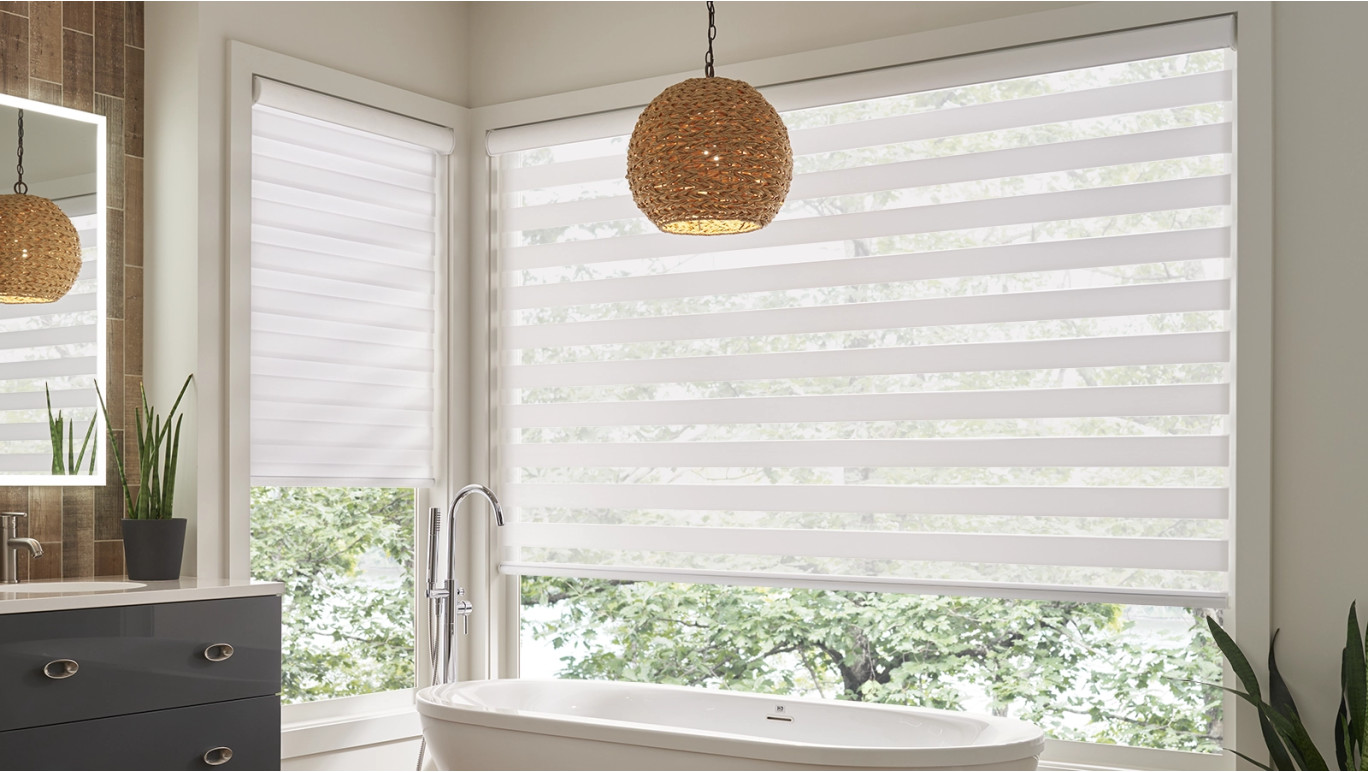 Bright sun filled bathroom featuring motorized white banded shades. 