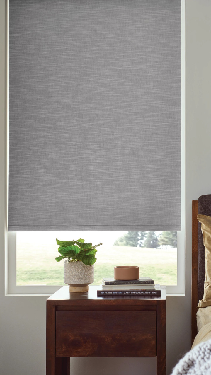 Close up of a gray roller shade in a bedroom window.