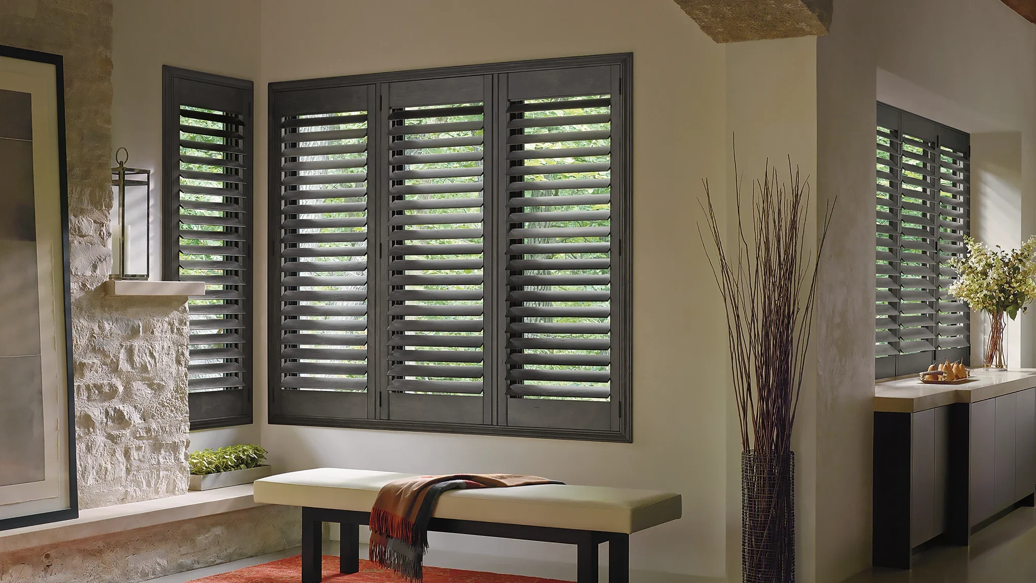 Gray wood window shutters with gear system in sitting area.
