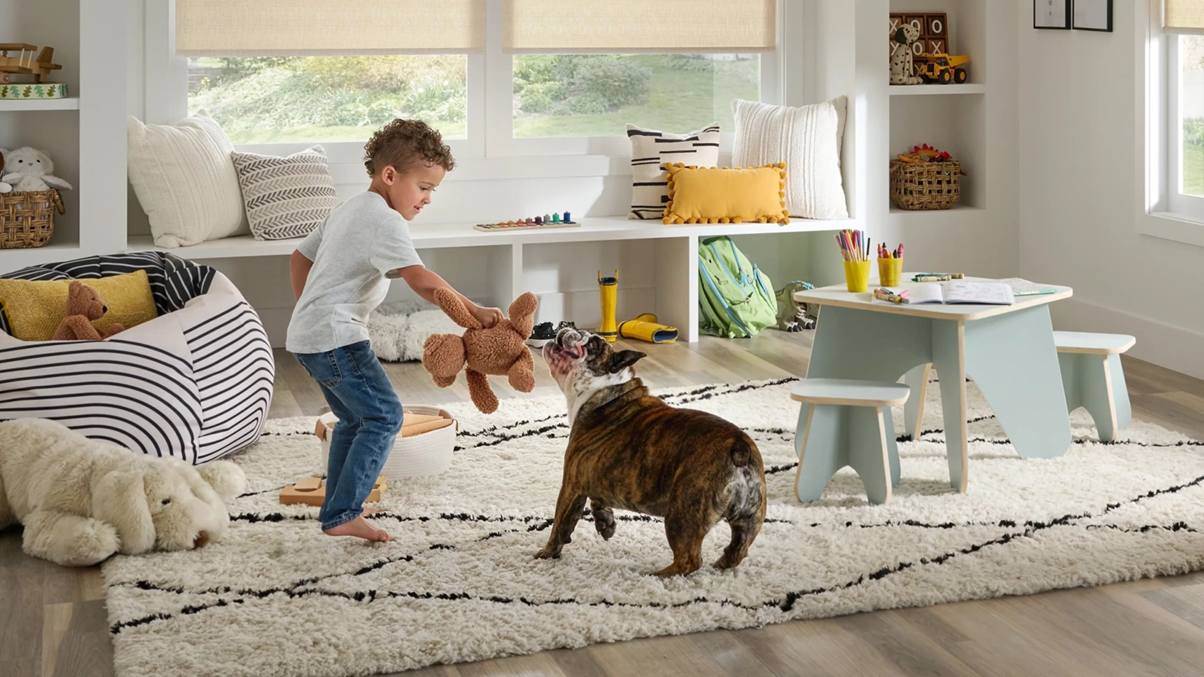 Little boy playing with his dog in a play room featuring child safe blinds.