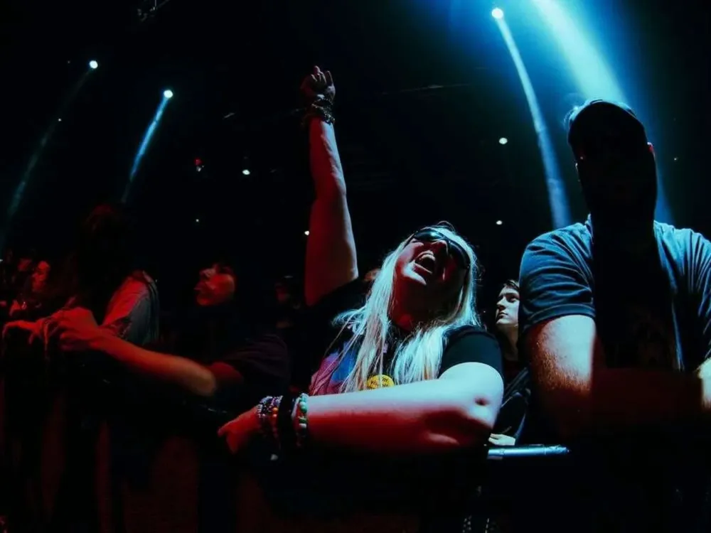 Scarlett in the crowd at a concert, everyone has their hands up, celebrating the performance together.