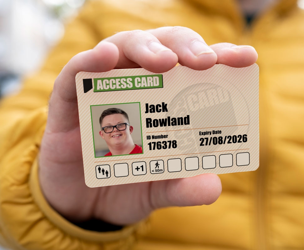 A person in a yellow jacket holding their access card. Showing crowd, +1 and distances symbols.